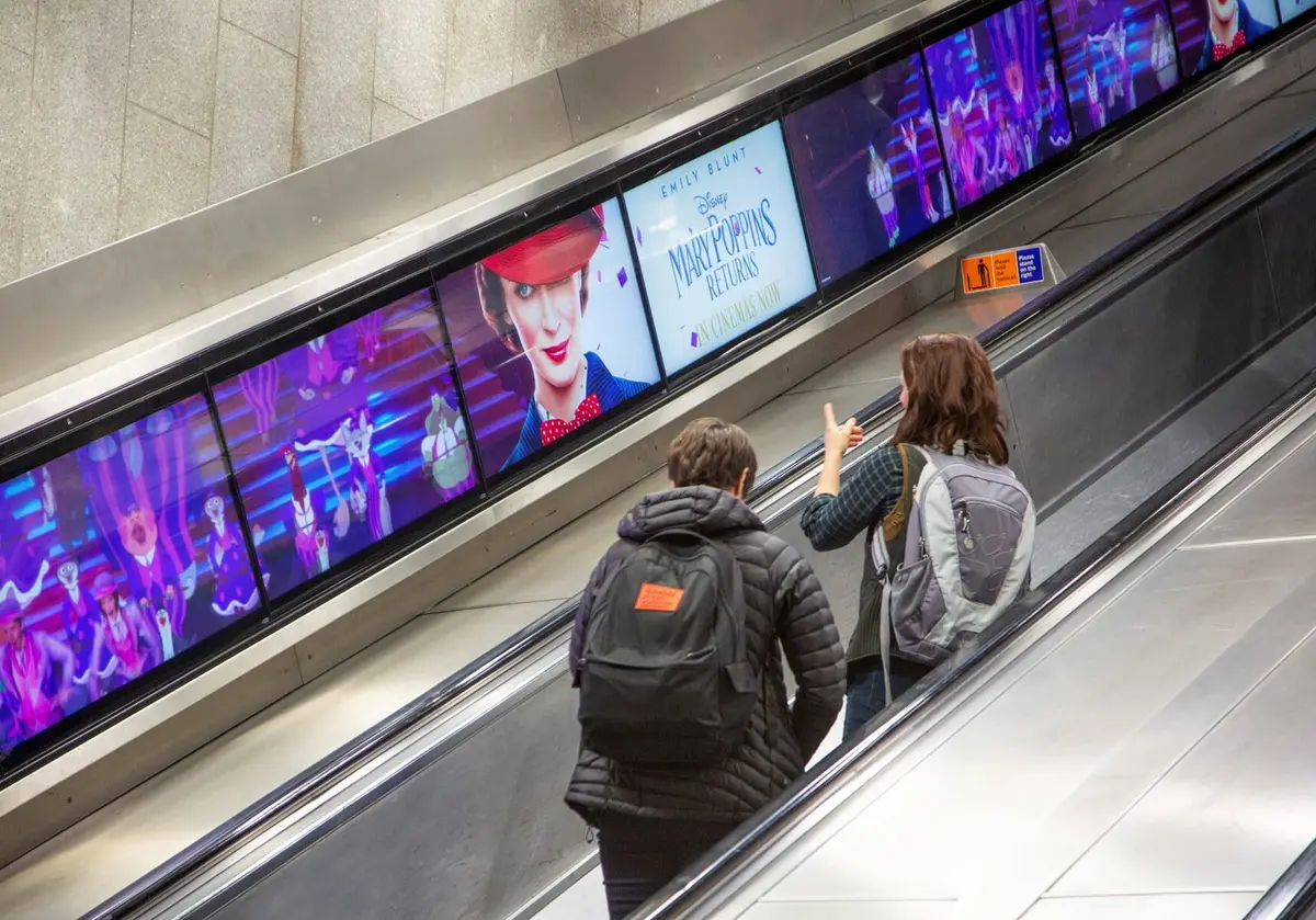 Full-motion digital advertising panels running alongside a London Underground escalator
