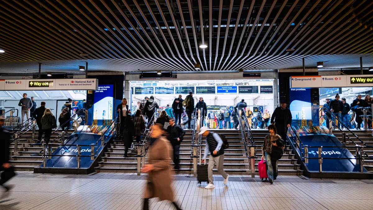 London Underground ticket hall with large digital advertising screens above the gates